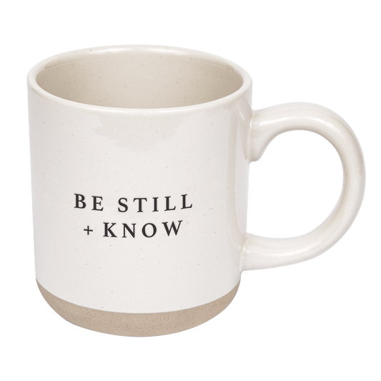 White mug with 'BE STILL + KNOW' text on a transparent background