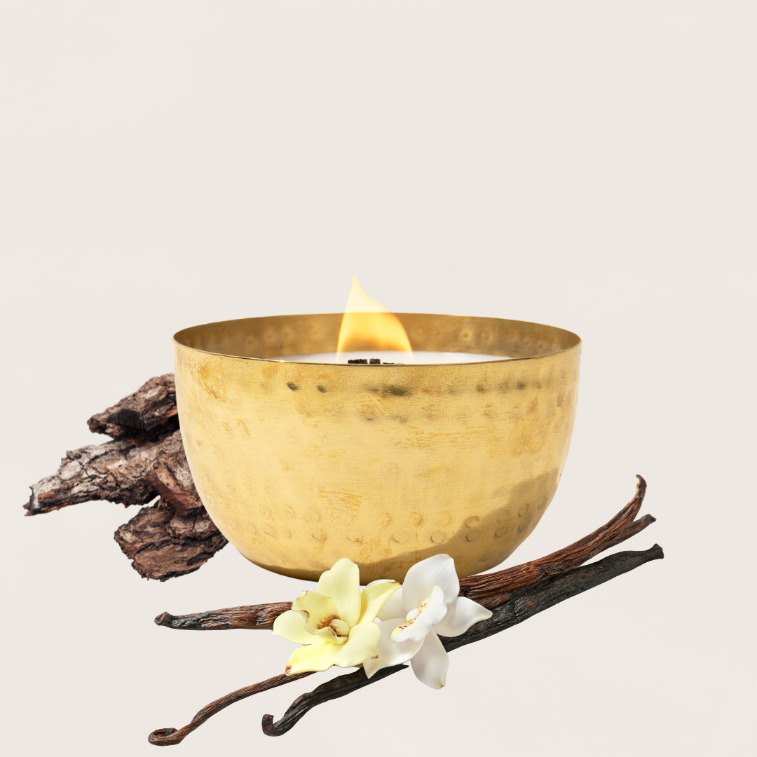 Cashmere Vanilla & Warm Amber – Solid Brass 14oz Pure Soy Candle - Gold bowl with a candle, vanilla beans, and flowers on a light background